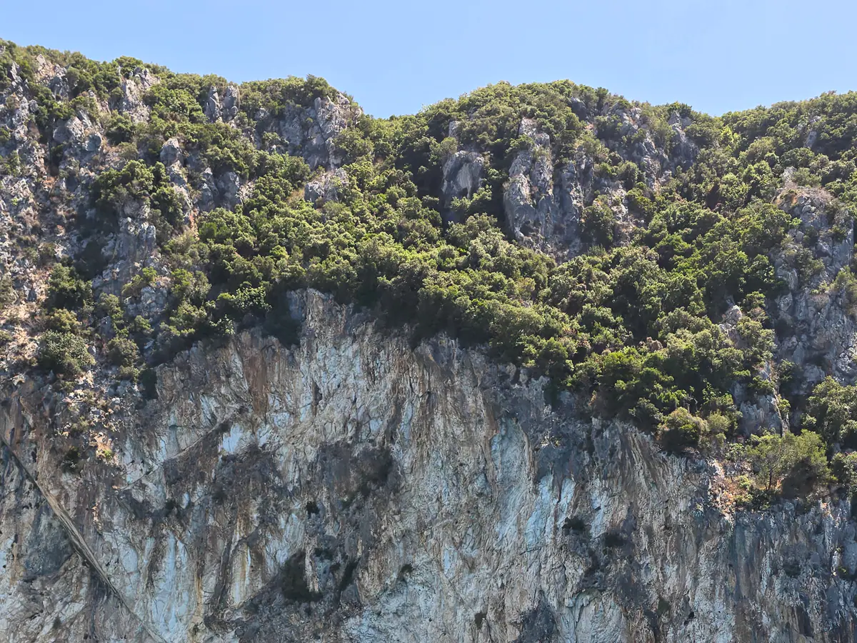 Blue water below a rocky cave wall on the coast