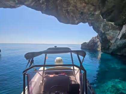 Dhermi Boat entering a sea cave with bright turquoise water
