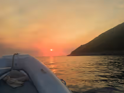 Sunset over the Dhërmi coast from the bow of the boat